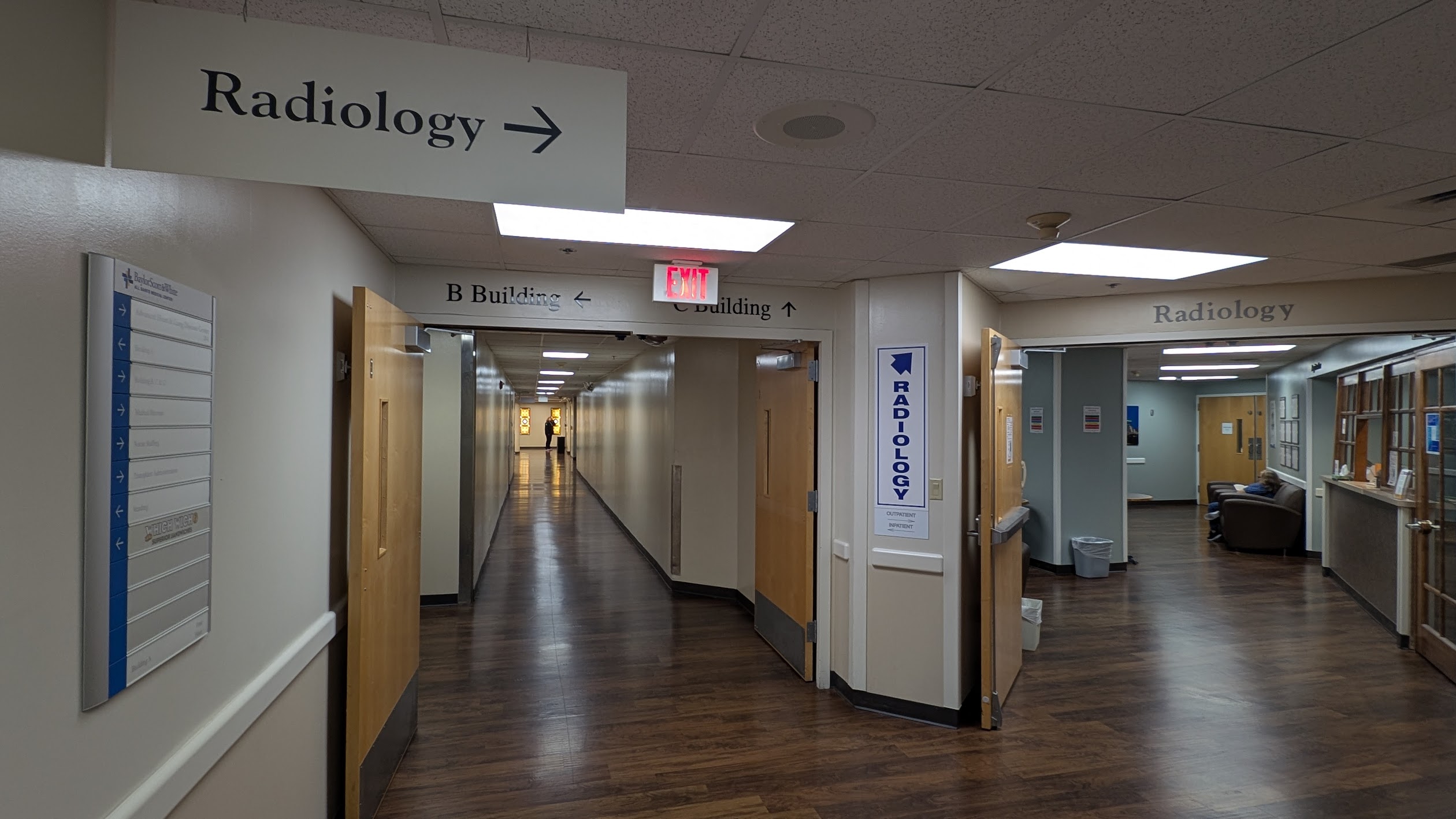 A BSWH hospital corridor lined with multiple overlapping directional signs pointing to Radiology, B Building, C Building, and more — illustrating the visual complexity patients navigate.